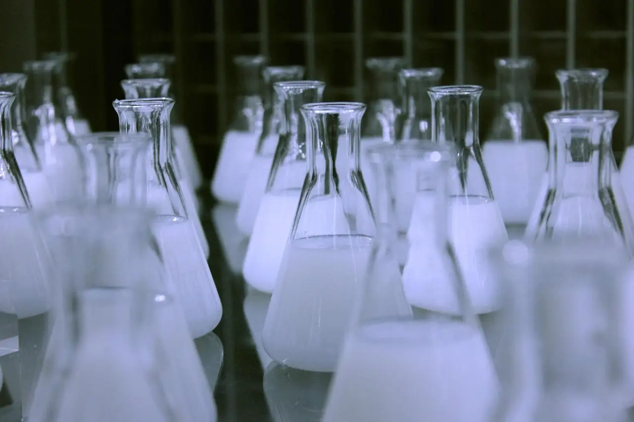 Glass laboratory flasks and measuring cylinders used for material testing.