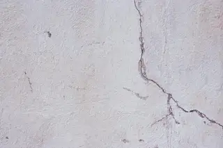 A long branching crack running down a rendered masonry wall.