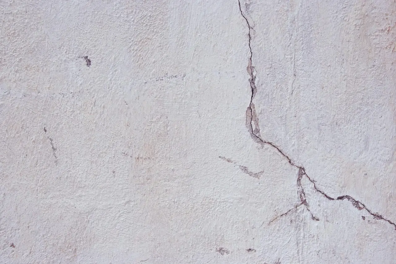A long branching crack running down a rendered masonry wall.
