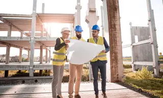 Engineers reviewing construction drawings together on site.