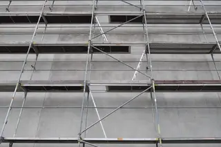 Scaffolding wrapped around the facade of a high-rise building under construction.